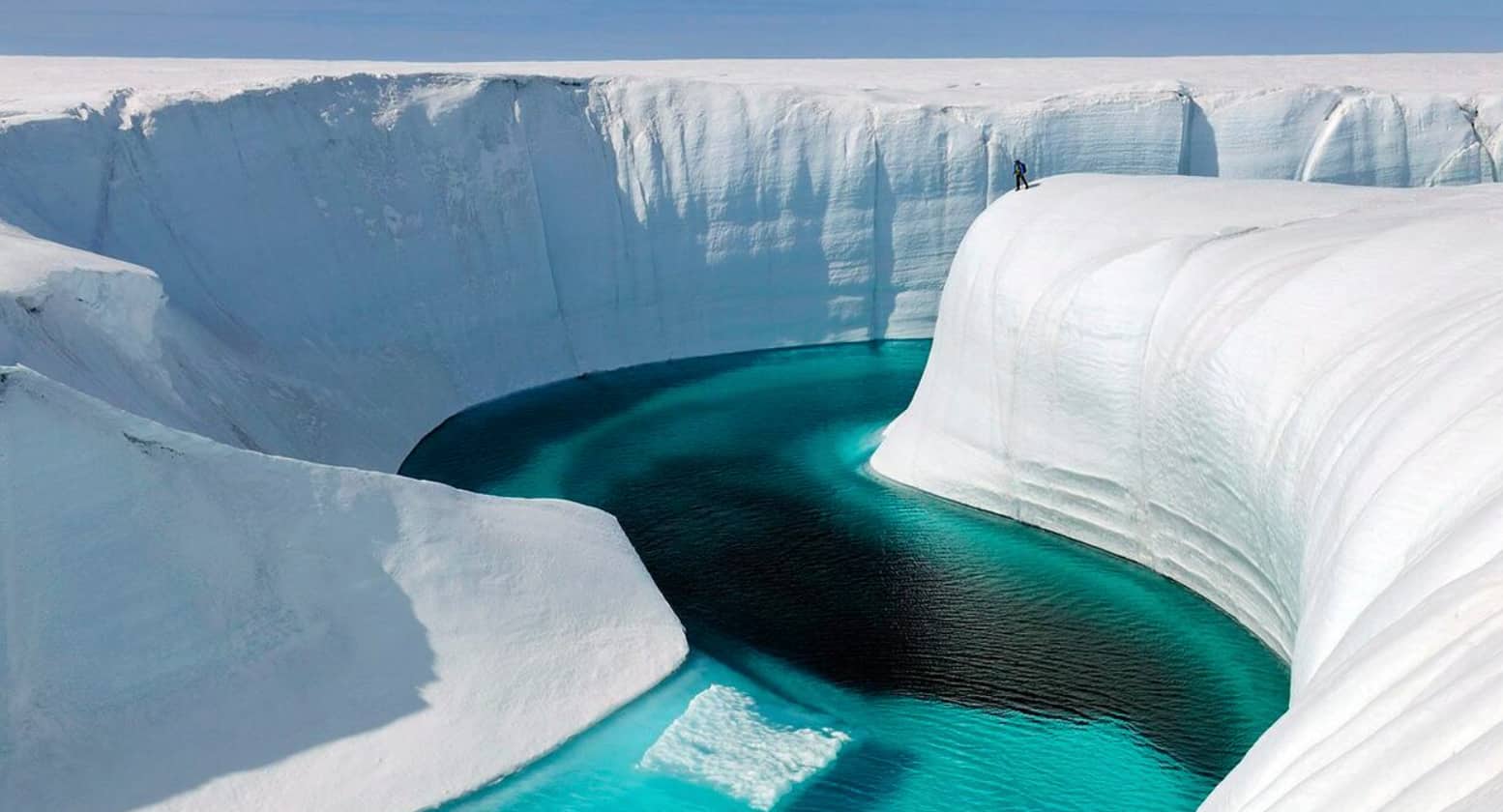 A shallow pool rests in the middle of a large, looming block of melting ice. 